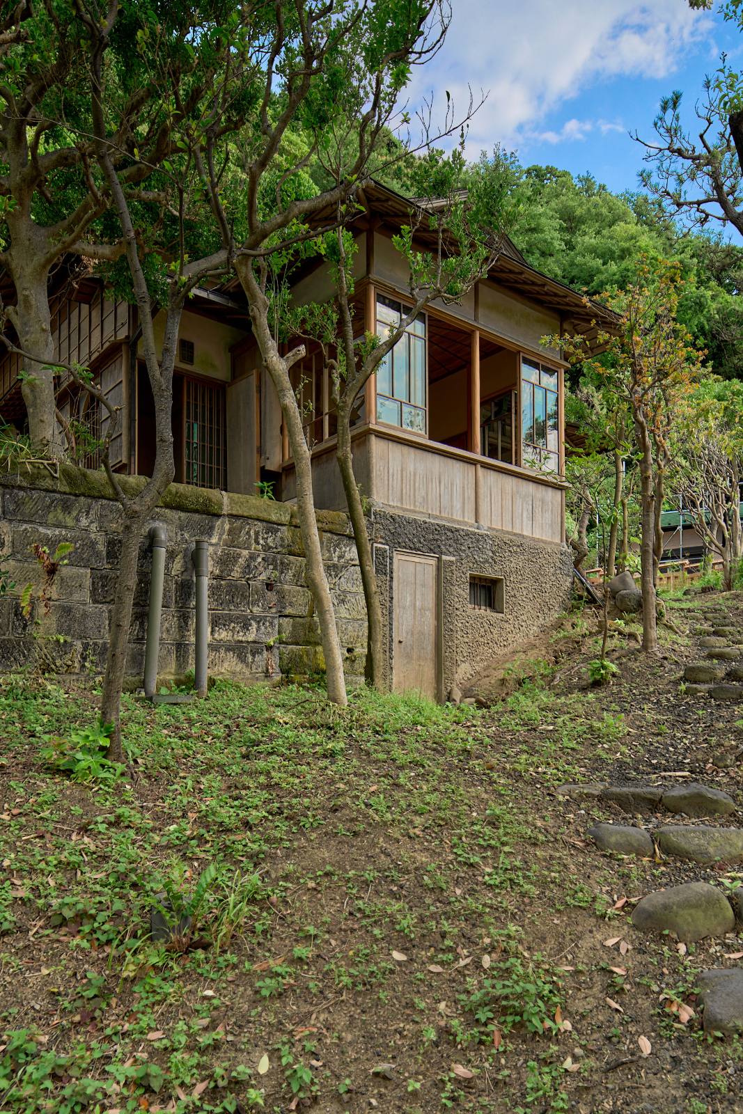 木立の中、石積みの上に建つ雨の念佛荘の離れ。