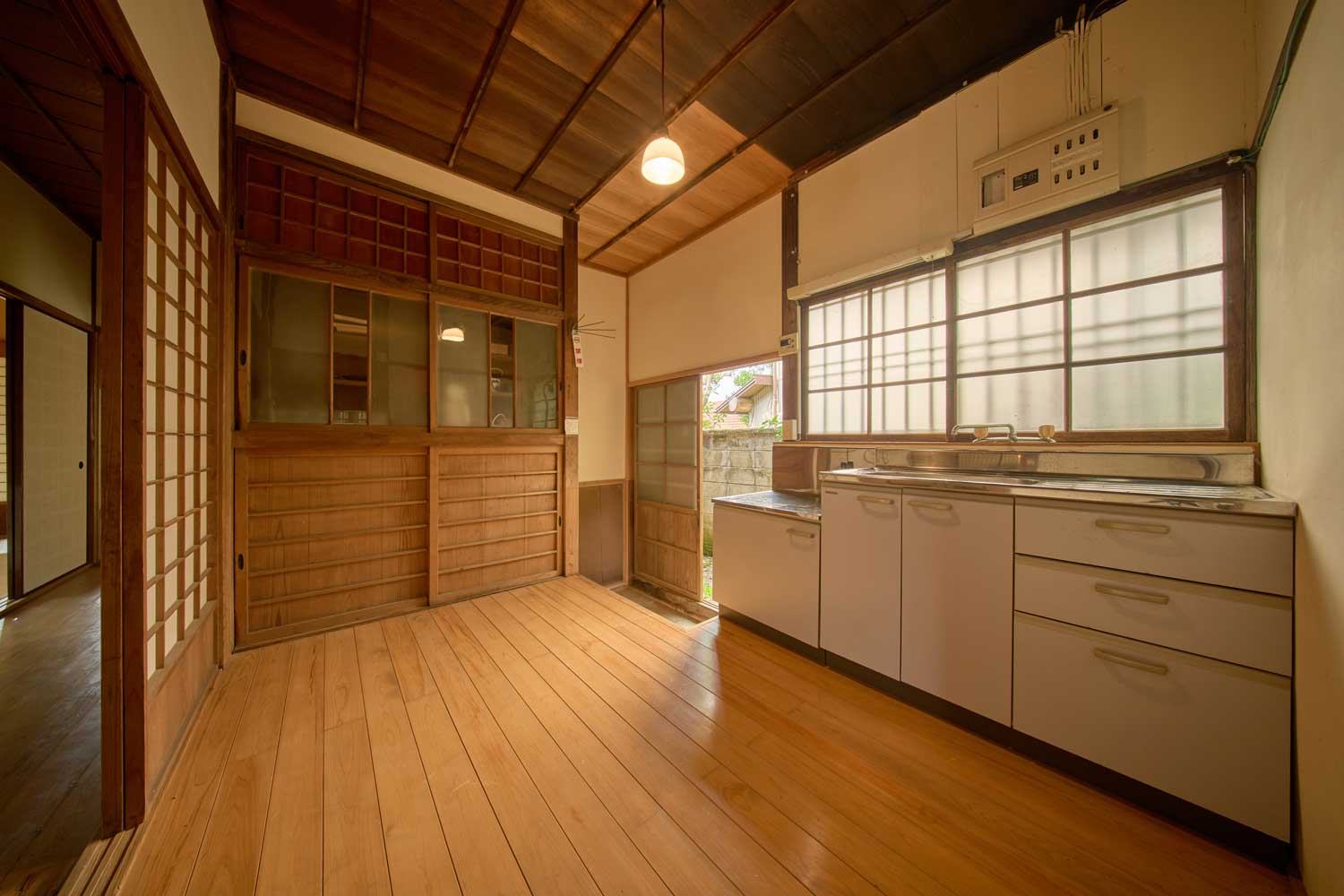 板張りの床と古い建具が残る台所。窓から光が入る。